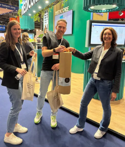 drie mensen staan naast elkaar en houden een cadeau boompje vast