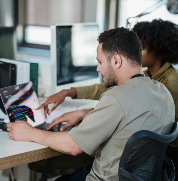 twee personen kijken naar een beeldscherm met code